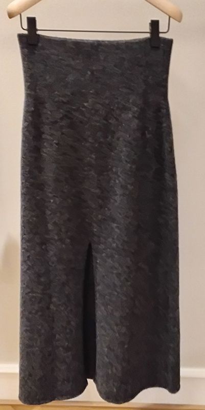 Dunkelgrauer gerader Midirock mit Schlitz vorne, hängt auf einem Holzbügel.