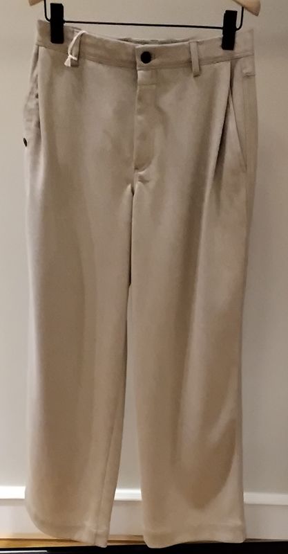 Beige Bundfaltenhose hängt auf einem Kleiderbügel.