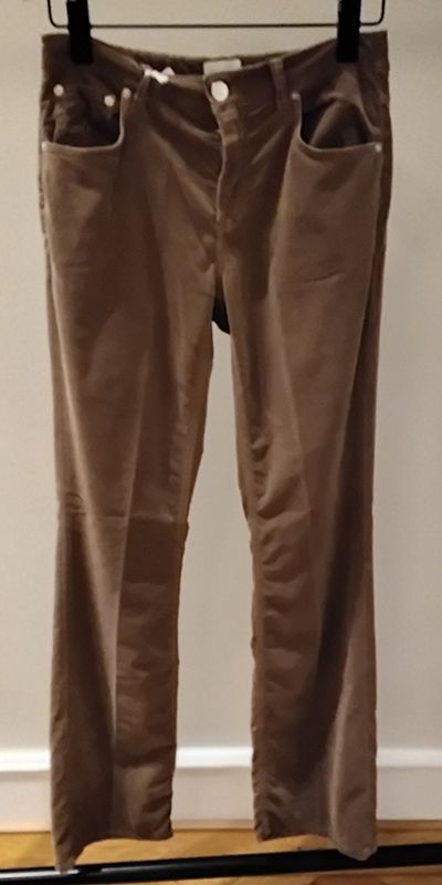 Braune Cordhosen hängen an einem schwarzen Kleiderbügel.