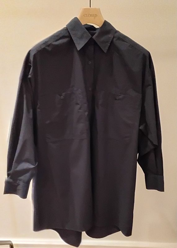 Dunkelblaues Button-Down-Hemd mit zwei Brusttaschen, das in einem Geschäft auf einem Kleiderbügel hängt.