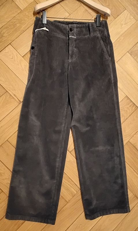 Graue Cordhosen hängen an einem hölzernen Kleiderbügel.