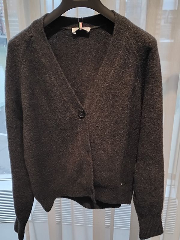 Dunkelgraue Strickjacke auf einem Kleiderbügel.