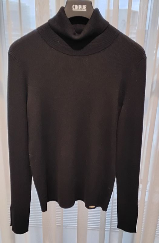 Schwarzer Rollkragenpullover auf einem Kleiderbügel vor hellem Hintergrund.