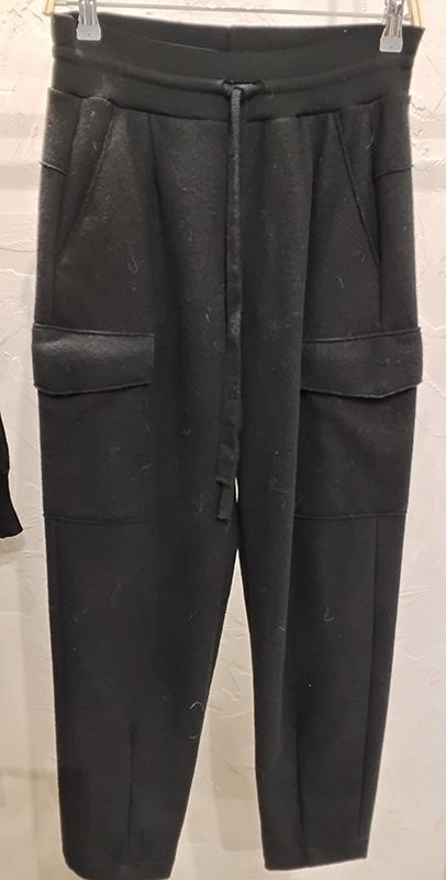 Schwarze Jogginghose mit Cargotaschen und Kordelzug im Bund hängt an einem Kleiderständer.