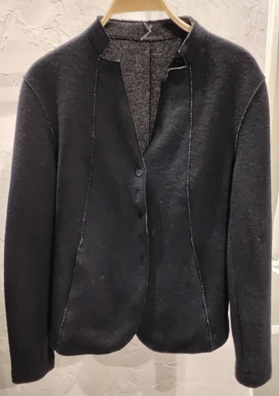 Schwarzer Blazer mit silbernen Ziernähten, hängt an einem Holzkleiderbügel.