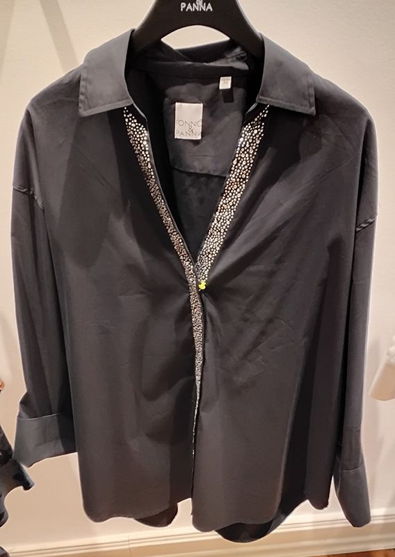 Dunkelgraues, geknöpftes Hemd mit Paillettenbesatz auf der Vorderseite, hängt an einem schwarzen Kleiderbügel.