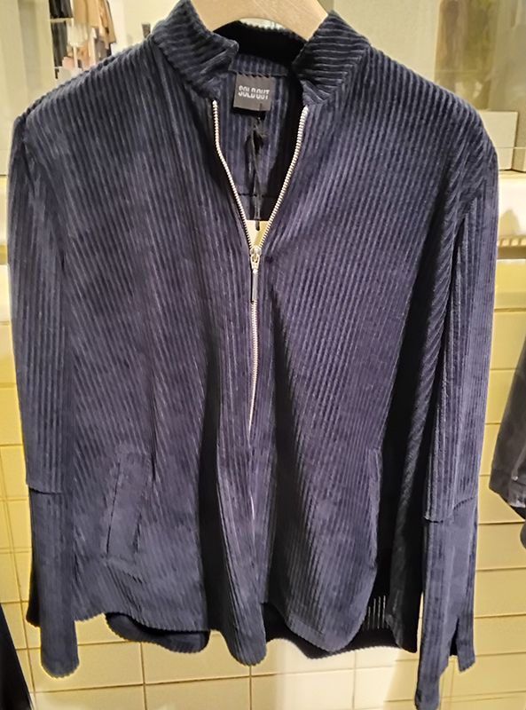 Blaues Cordhemd mit Reißverschluss und Stehkragen hängt an einem Kleiderständer.