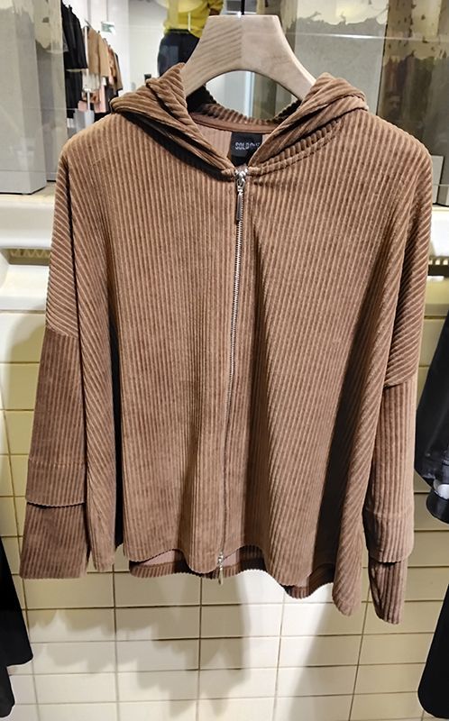 Brauner Cord-Kapuzenpullover mit Reißverschluss hängt an einem Kleiderständer.