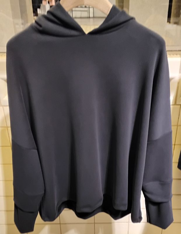 Schwarzer Kapuzenpullover auf einem Kleiderbügel, drinnen.