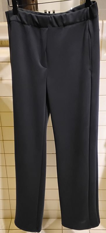 Schwarze Hose hängt an einem Kleiderbügel, Nahaufnahme. Elastischer Bund und gerades Bein.