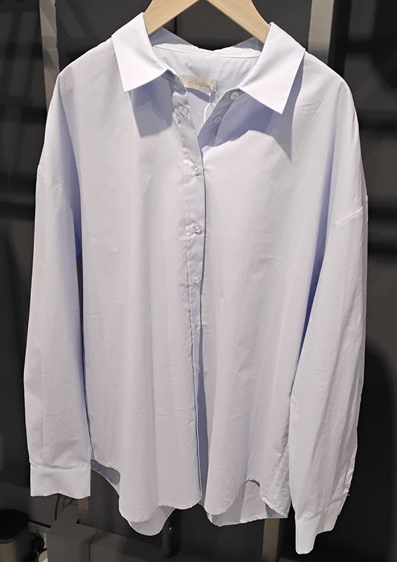 Hellblaues Button-Down-Hemd mit Kragen hängt auf einem Holzbügel.