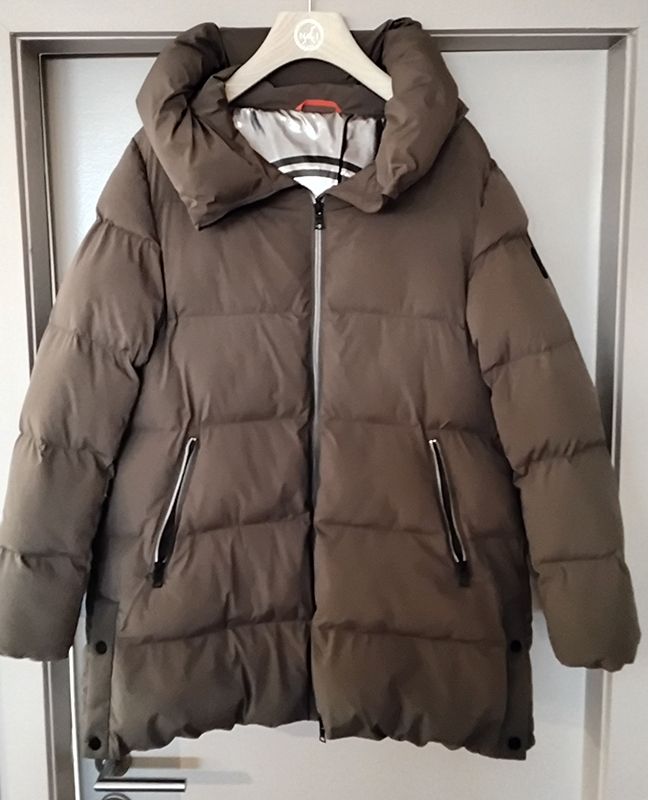 An einer Tür hängt eine braune Pufferjacke mit Reißverschluss und großer Kapuze.