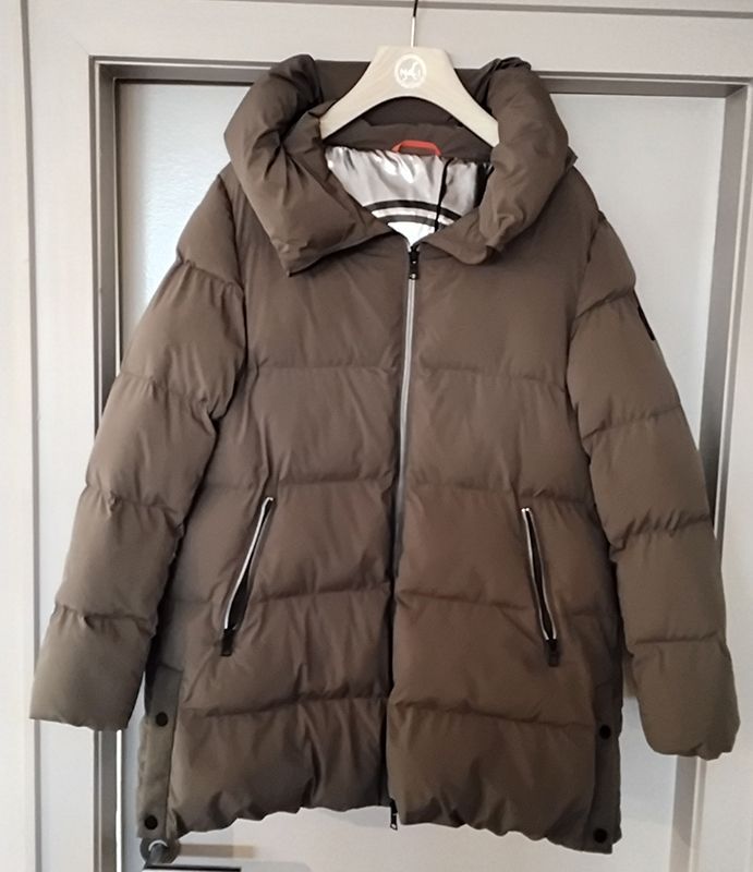 Braune Pufferjacke mit Kapuze hängt an einem weißen Kleiderbügel.