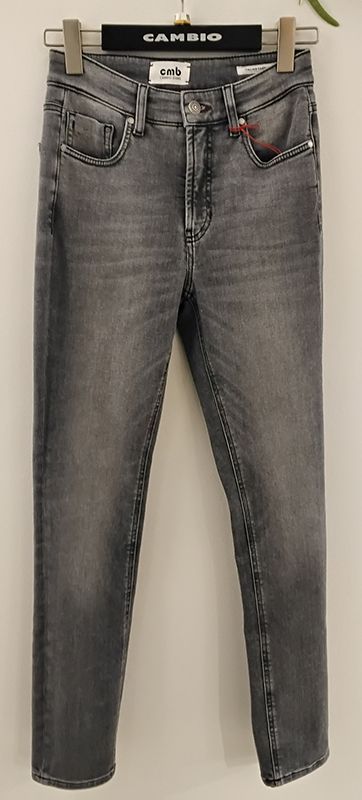 Graue Jeans hängen an einem Holzkleiderbügel vor einer weißen Wand.