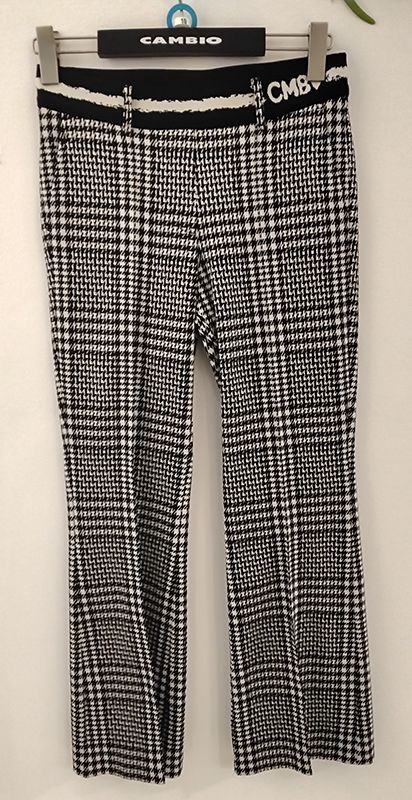 Schwarz-weiß karierte Hose, die an einem Kleiderbügel hängt, mit einem CMB-Logo am Bund.