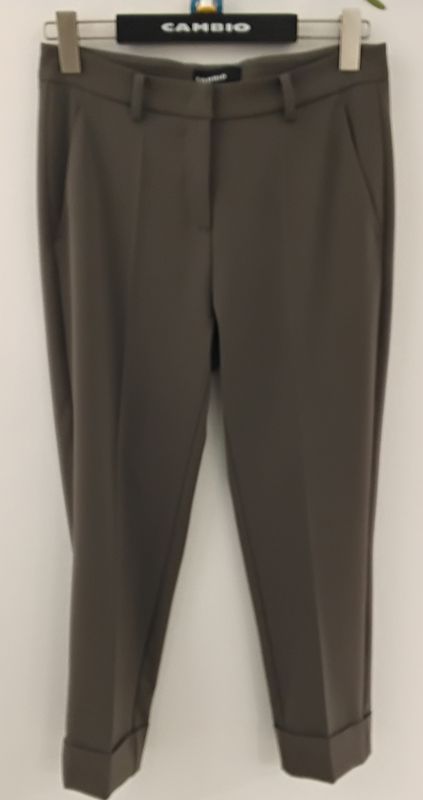 Olivgrüne, knöchellange Damenhosen hängen an einem Kleiderbügel, die Hosenbeine sind umgeschlagen.