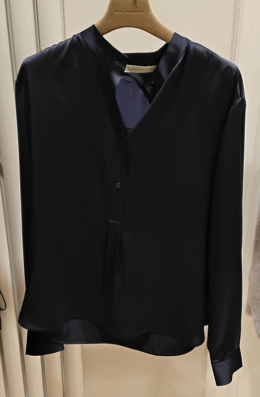 Dunkelblaue Bluse hängt auf einem Kleiderbügel.