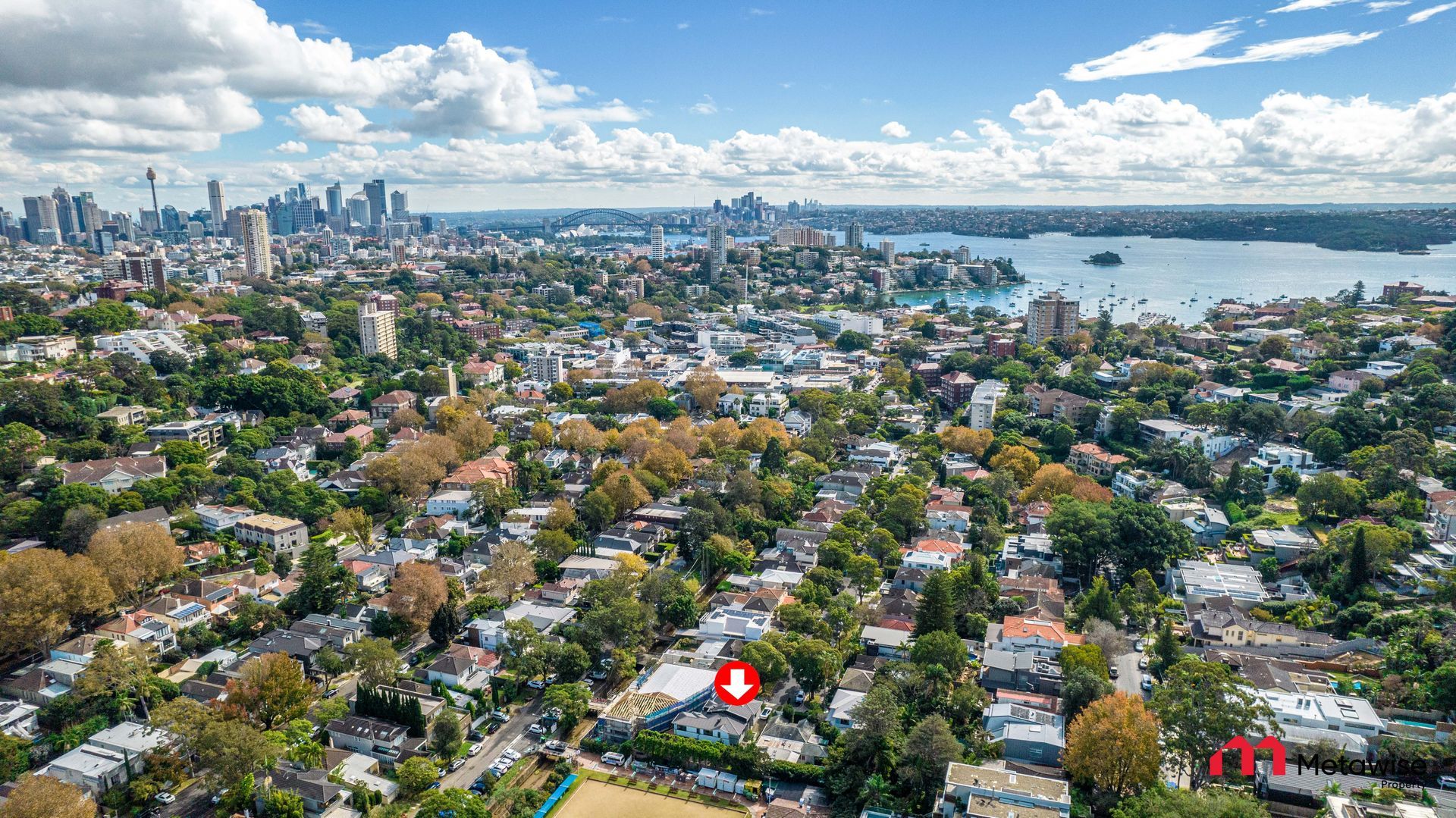 An aerial view of a city with a red arrow pointing to a building.