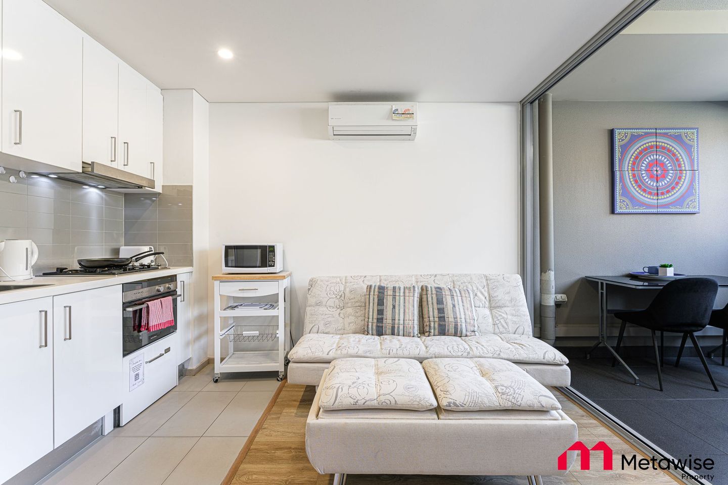 A living room with a couch and a kitchen in a small apartment.