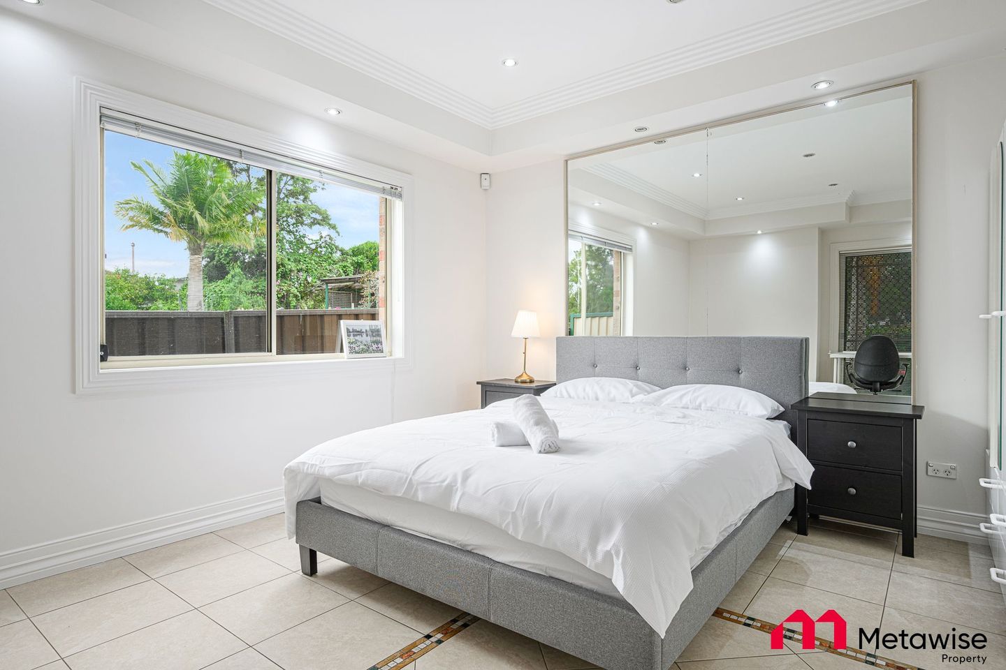 A bedroom with a large bed and a mirror on the wall.