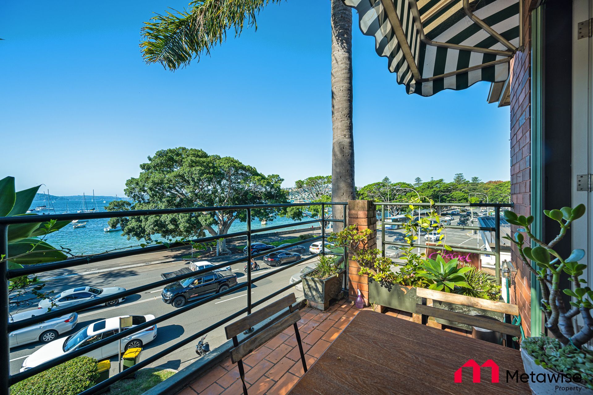 A balcony with a view of the ocean and a black and white awning