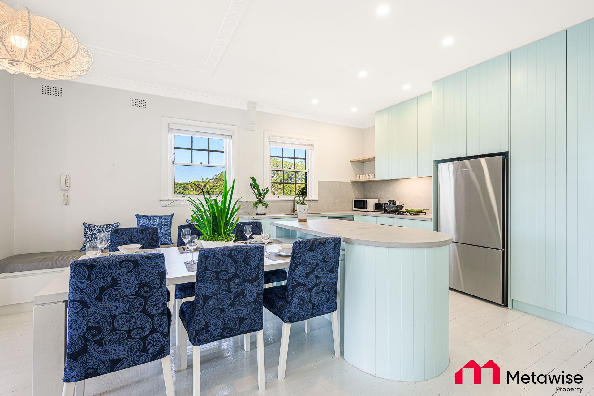 A kitchen with a table and chairs and a stainless steel refrigerator