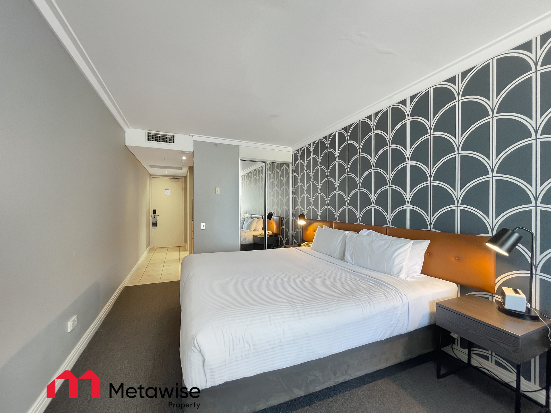 A hotel room with a king size bed and a nightstand.