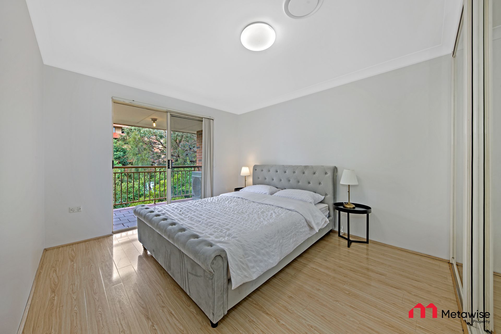 A bedroom with a large bed and a balcony.