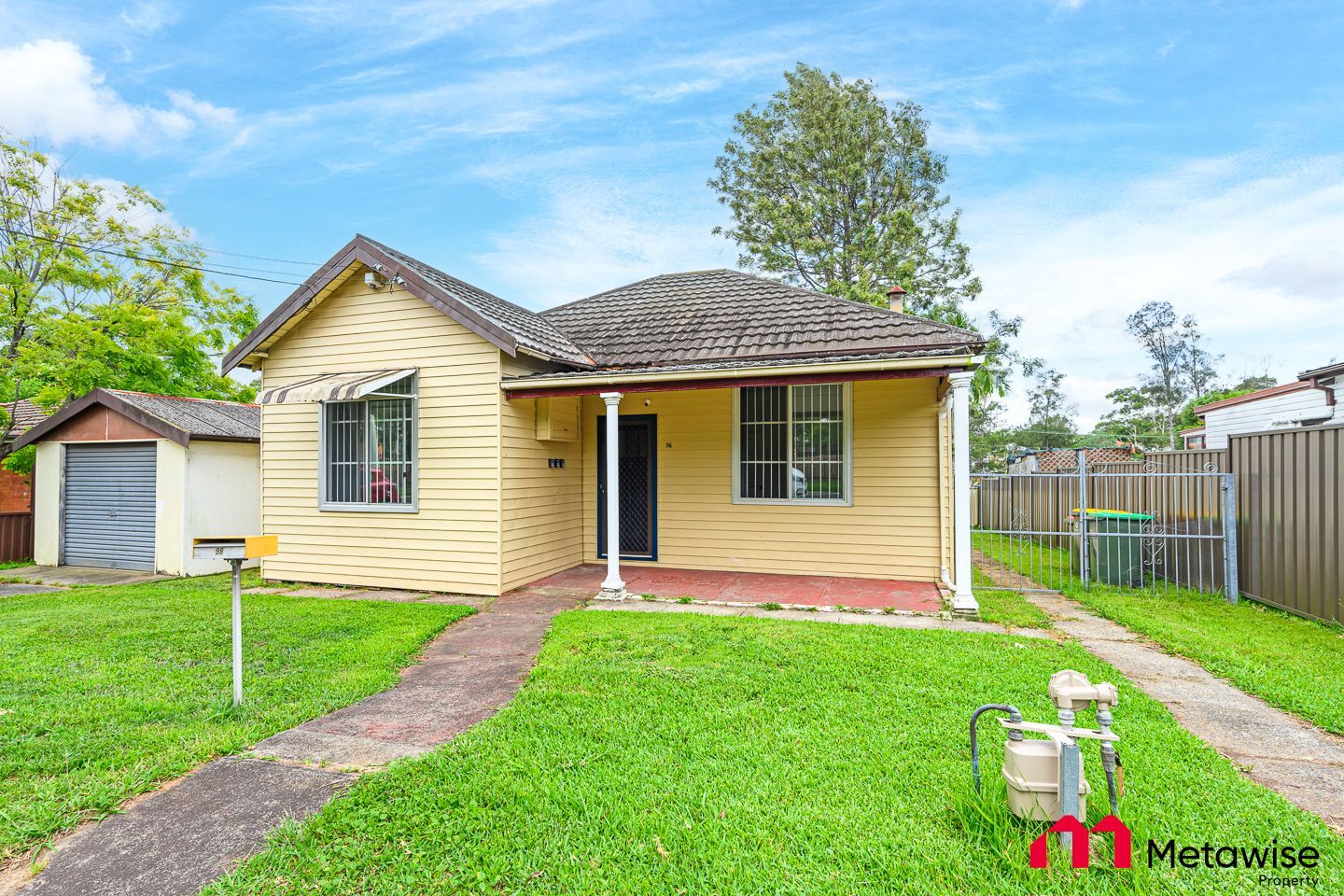 A small yellow house with a large lawn in front of it.