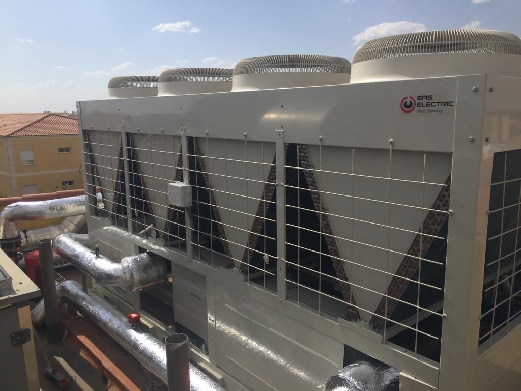 Unidades de climatización en azotea con grandes rejillas de ventilación y cubiertas para ventiladores. Un día soleado.