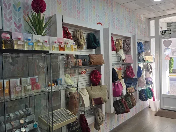 Interior de una tienda con estanterías de perfumes, bolsos, joyas y accesorios.