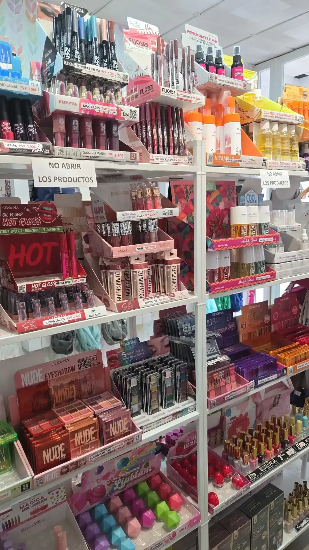 Estantes repletos de diversos cosméticos en un establecimiento minorista, incluidos maquillaje, pinceles y esmaltes de uñas.