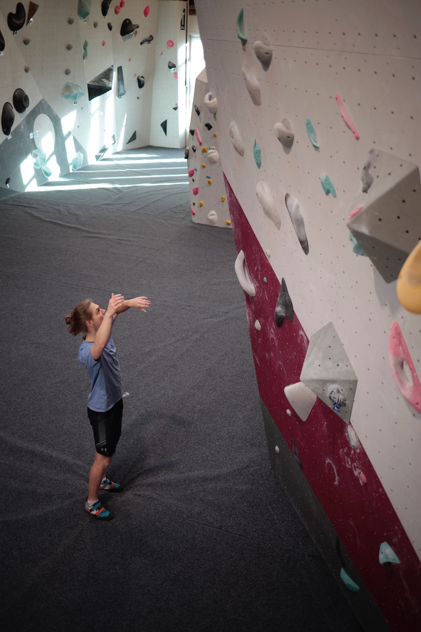 Eine Frau steht vor einer Kletterwand