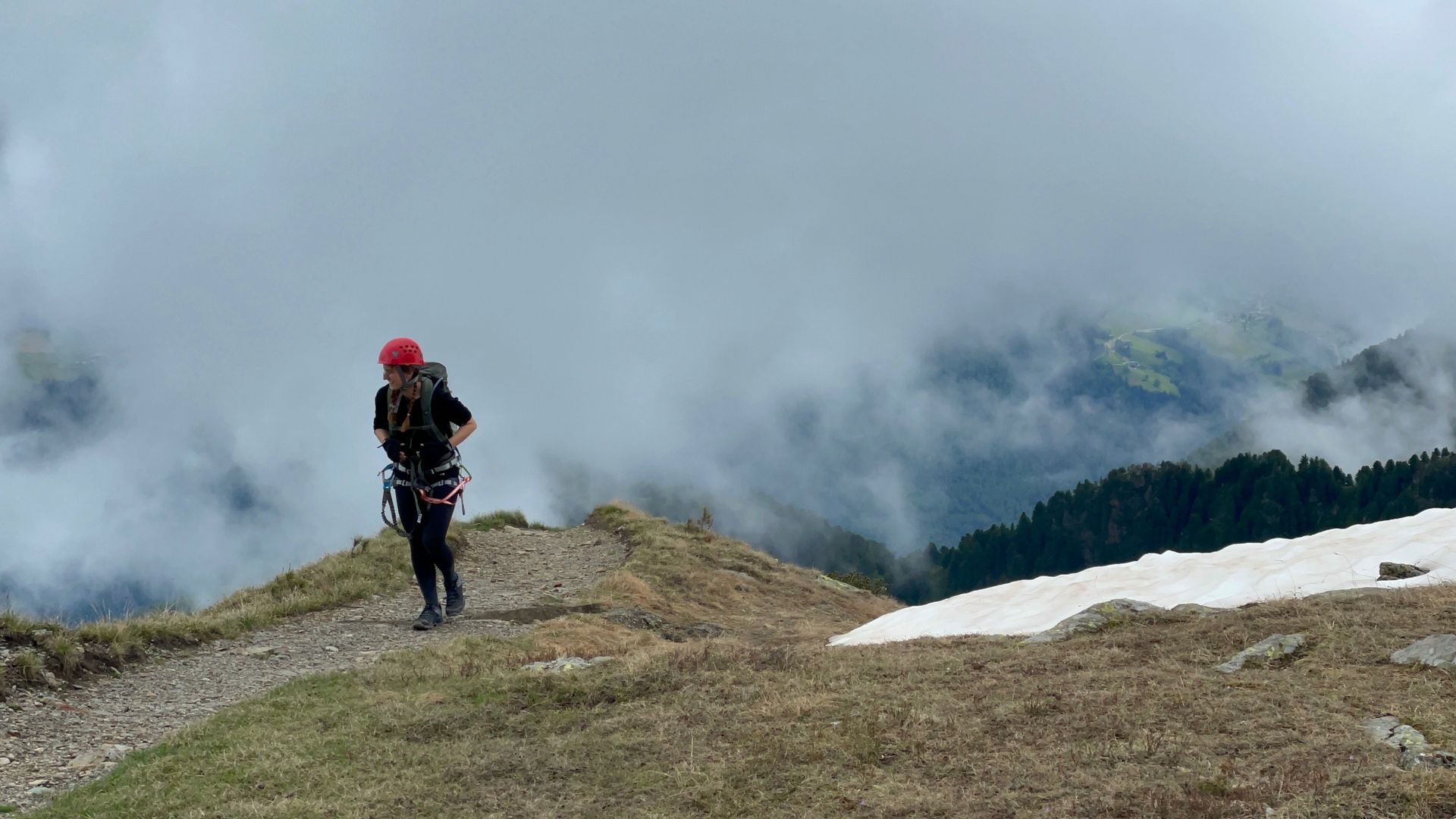Eine Person mit einem Rucksack geht auf einem Berggipfel spazieren.