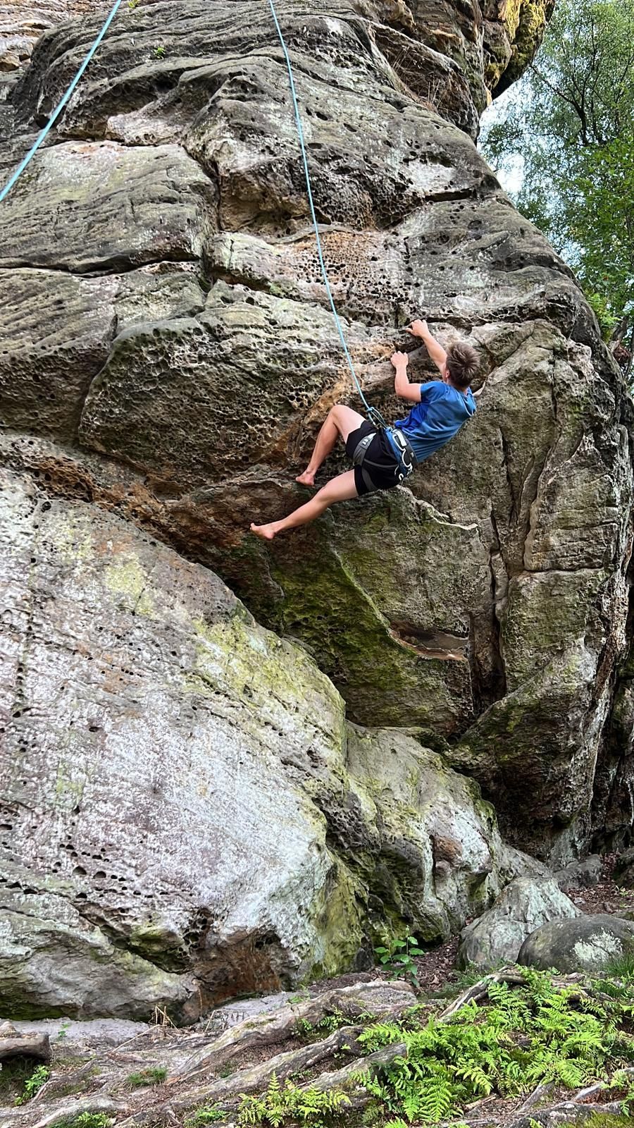 Ein Mann klettert die Seite eines großen Felsens hinauf.