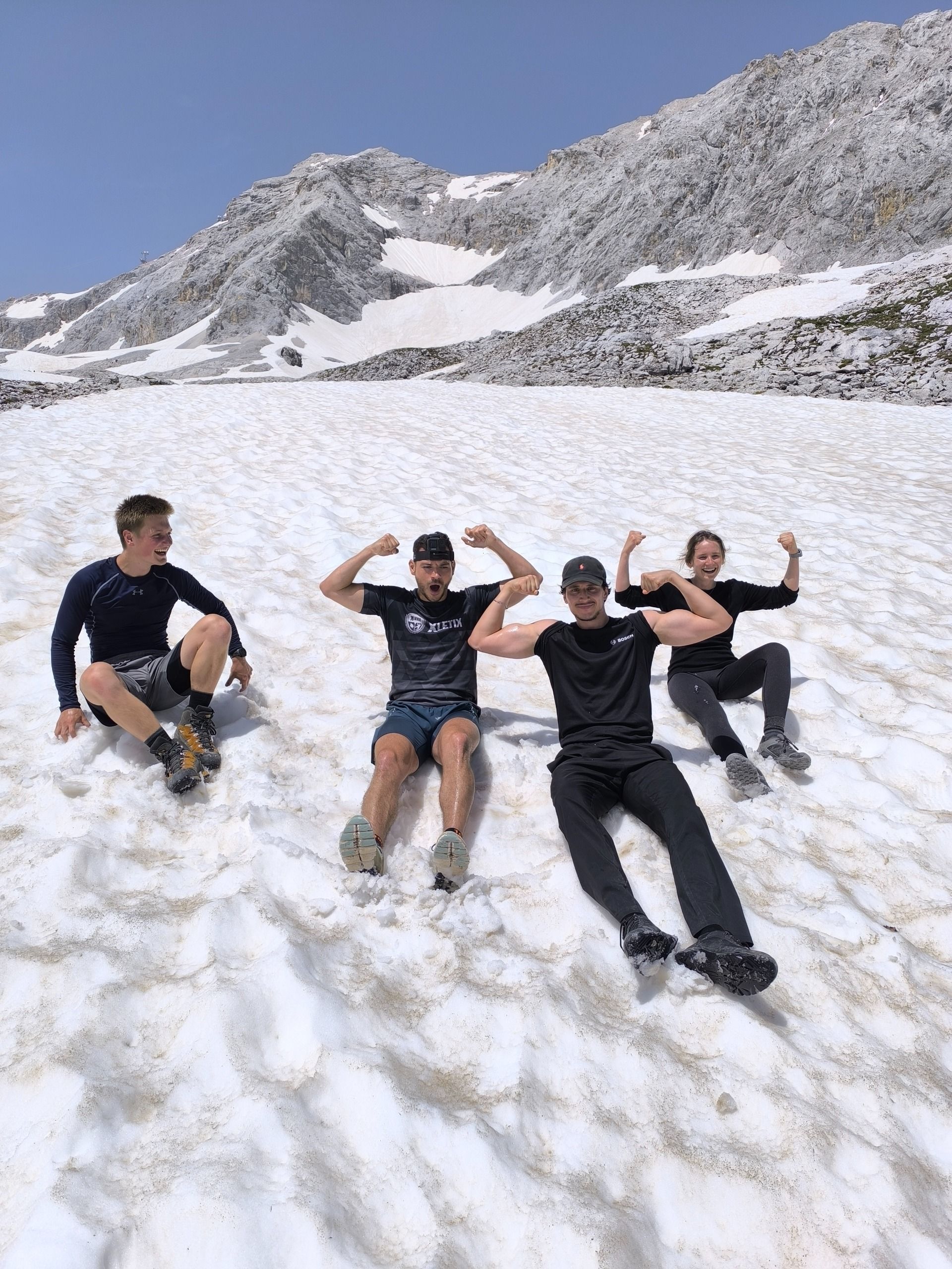 Eine Gruppe von Menschen liegt auf einem schneebedeckten Berggipfel.