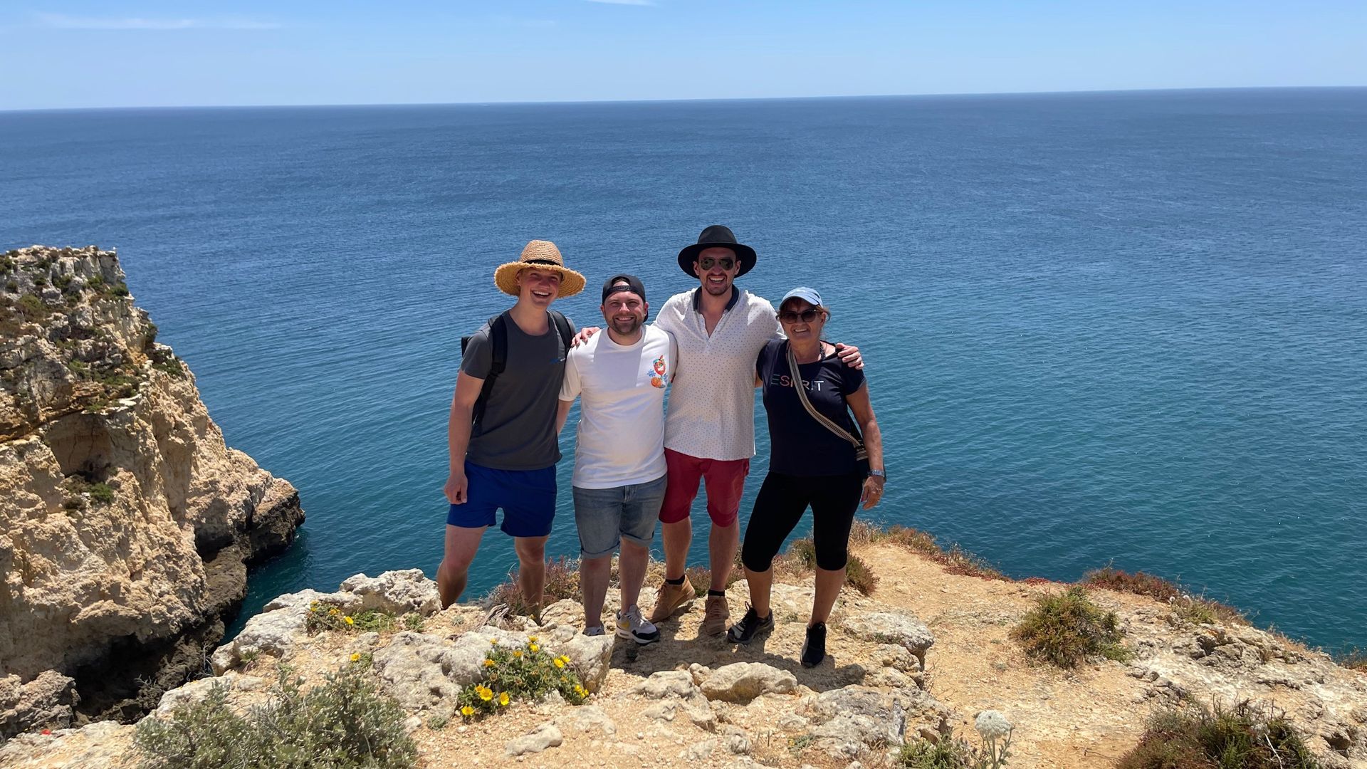 Eine Gruppe von Menschen steht auf einer Klippe und blickt auf den Ozean.