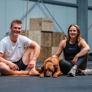 Ein Mann und eine Frau sitzen mit einem Hund auf dem Boden