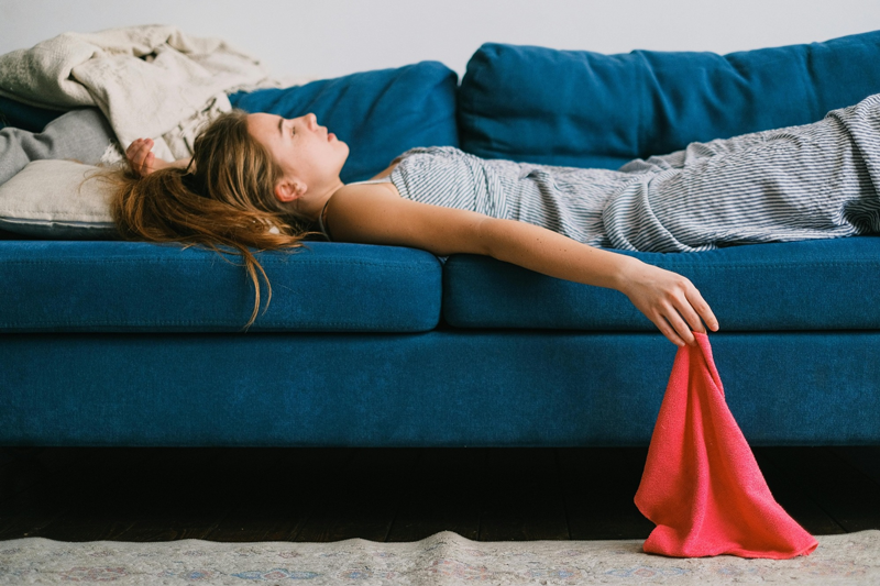 Eine Frau liegt auf einem blauen Sofa und hält ein rotes Tuch.