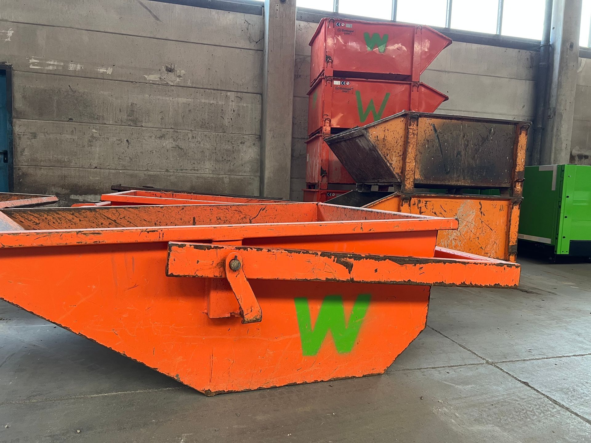 Eine orangene Schuttermulde mit grünem W