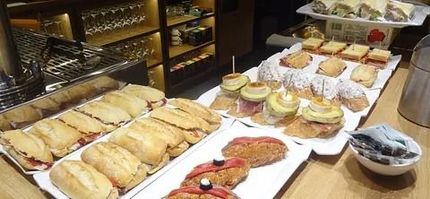 Una exhibición de varios sándwiches pequeños, tapas y pintxos en un mostrador en un bar.