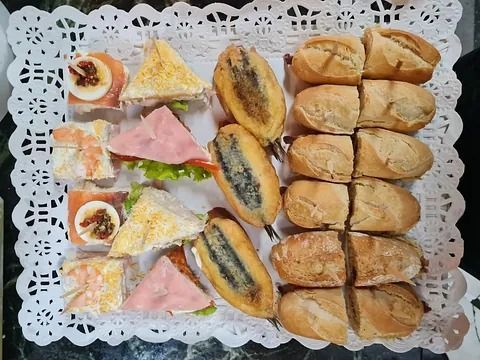 Surtido de sándwiches y panecillos en una bandeja blanca estampada.