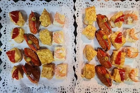 Dos bandejas de tapas, con varios bocadillos salados servidos sobre manteles de encaje.