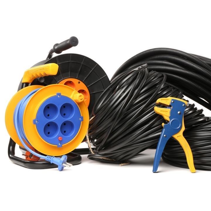 Carrete de cable alargador amarillo y azul, cables negros y pelacables.