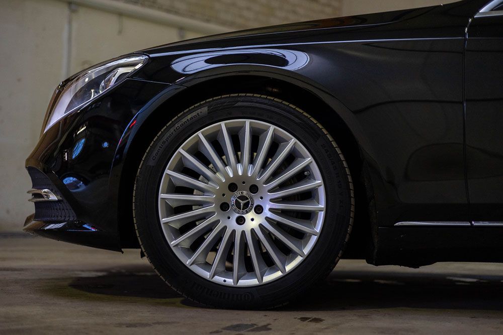 Eine Nahaufnahme des Rades eines schwarzen Autos in einer Garage.