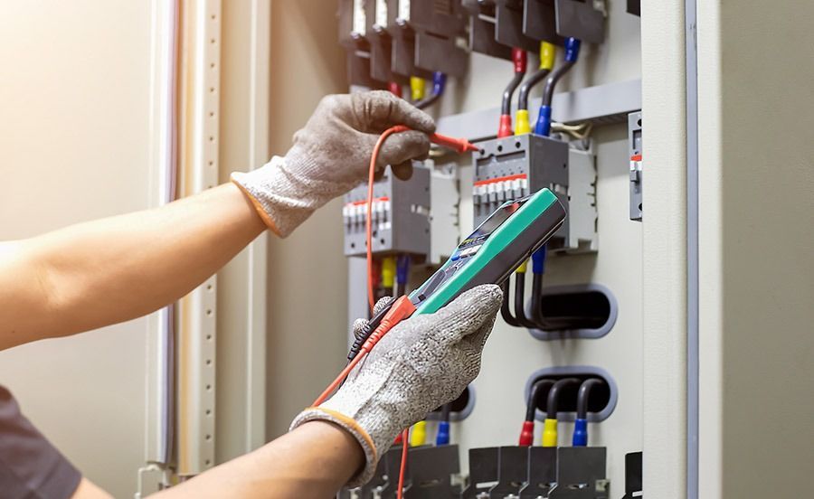 Un electricista está trabajando en una caja eléctrica con un multímetro.