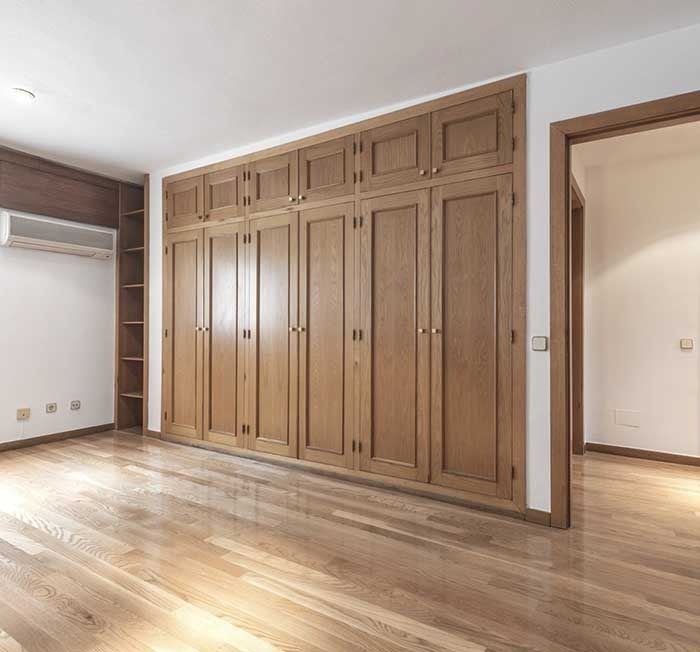 Una habitación vacía con gabinetes de madera y pisos de madera.