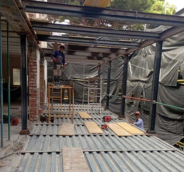 Un hombre está de pie sobre un andamio en un edificio en construcción.