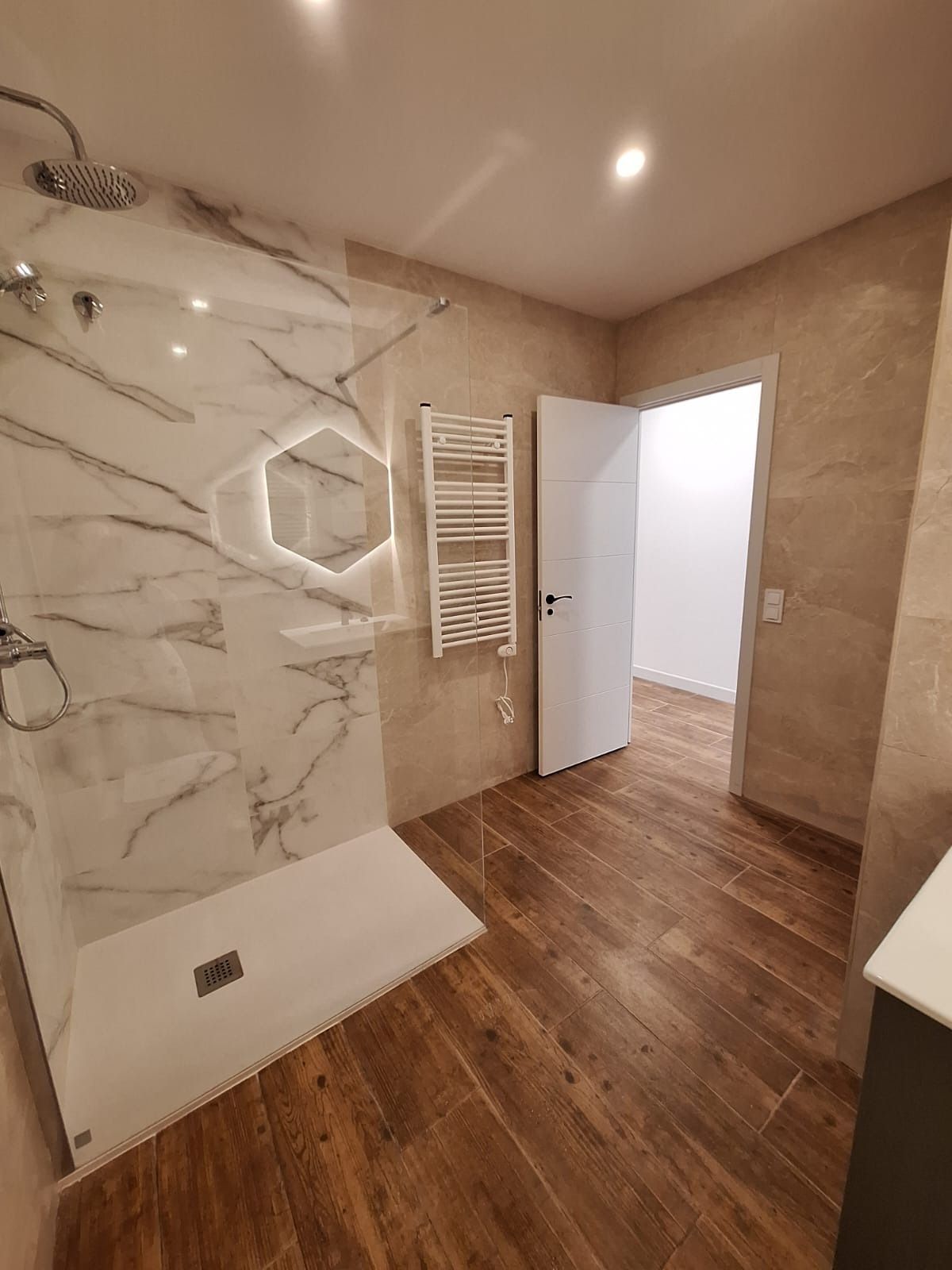 Un baño con ducha a ras de suelo y suelo de madera.