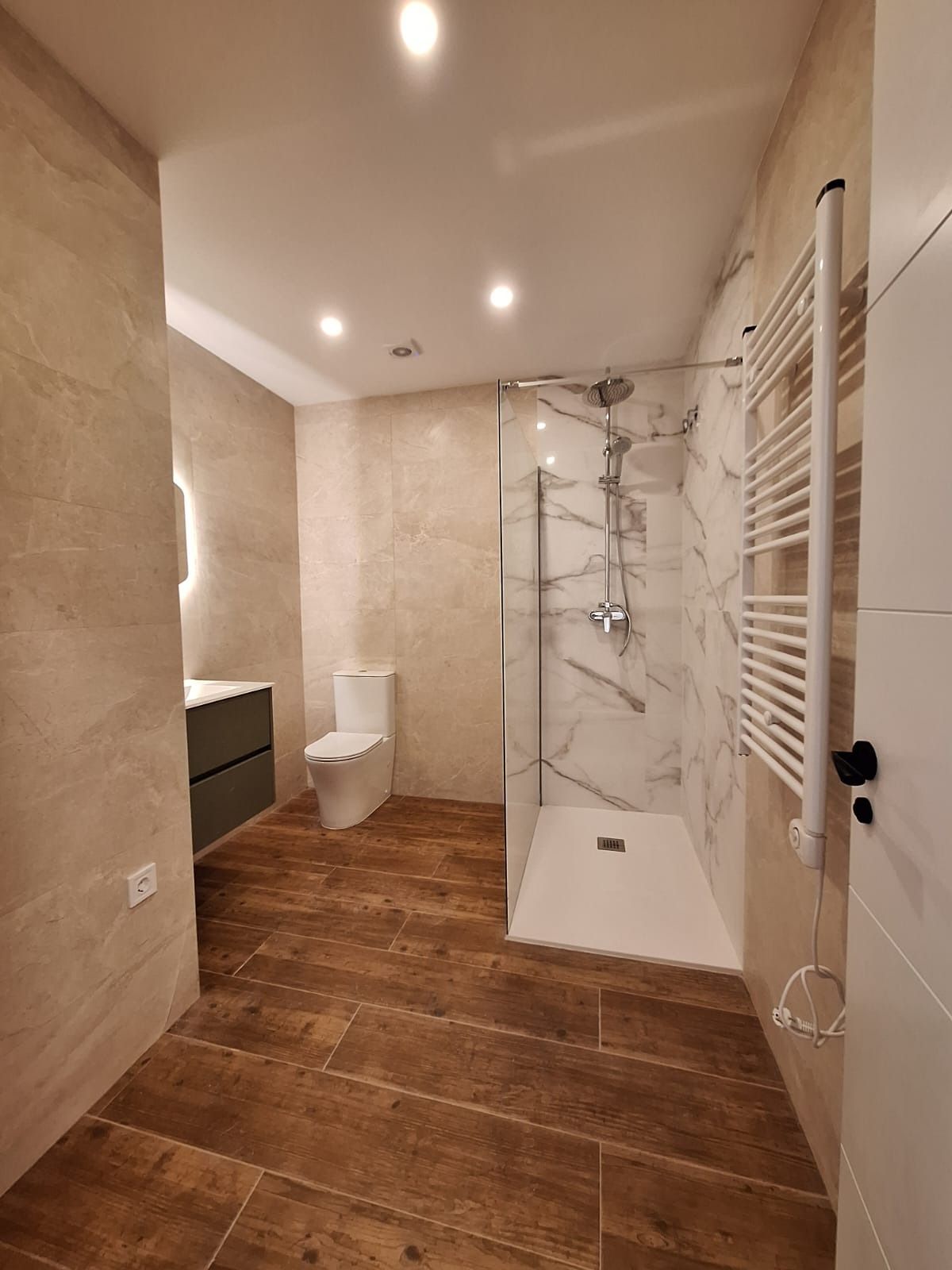 Un baño con ducha a ras de suelo y un inodoro.